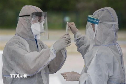 Nhân viên y tế lấy mẫu xét nghiệm COVID-19 tại Berlin, Đức. (Ảnh: AFP/TTXVN)