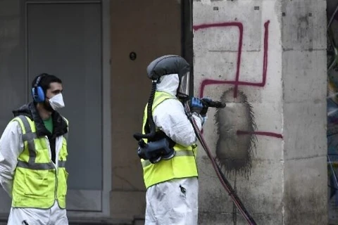 Làm sạch biểu tượng phátxít Đức được vẽ lên một cây cột ở dọc con phố Rue De Rivoli. (Nguồn: AFP)
