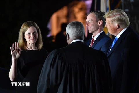 Bà Amy Coney Barrett (trái) tuyên thệ nhậm chức Thẩm phán Tòa án Tối cao trước sự chứng kiến của Tổng thống Mỹ Donald Trump (phải) tại Nhà Trắng ở Washington, DC. (Ảnh: AFP/TTXVN)