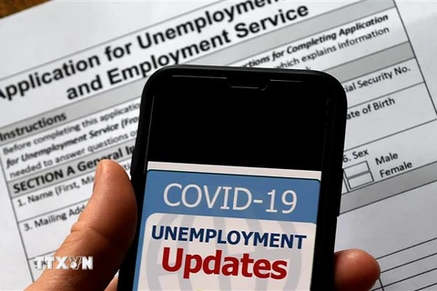 Cập nhật tình hình mất việc làm do dịch COVID-19 trên điện thoại tại Arlington, bang Virginia, Mỹ. (Ảnh: AFP/TTXVN)