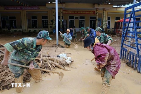 Bộ đội giúp địa phương xã Hướng Việt thu dọn bùn đất tại trường học. (Ảnh: Hồ Cầu/TTXVN)