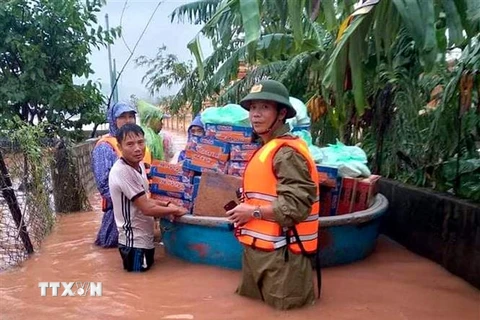 Ông Phan Thanh Miên (phải) dầm mưa, lội nước lũ cùng các đoàn cứu trợ đi cấp phát nhu yếu phẩm tiếp tế cho bà con trong đợt mưa lũ lịch sử vừa qua. (Ảnh: TTXVN phát)