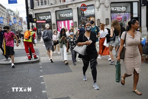 Người dân đeo khẩu trang phòng lây nhiễm COVID-19 khi di chuyển trên đường phố tại London, Anh. (Ảnh: AFP/TTXVN)