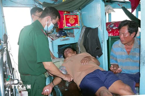 Quân y Bộ đội Biên phòng Sóc Trăng thăm khám sức khoẻ ban đầu cho 2 ngư dân gặp nạn. (Ảnh: Trung Hiếu/TTXVN)