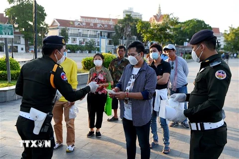 Lực lượng quân cảnh Campuchia phát khẩu trang miễn phí cho người dân tại Phnom Penh. (Ảnh: AFP/TTXVN)