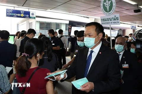Phó Thủ tướng kiêm Bộ trưởng Y tế Thái Lan Anutin Charnvirakul (phải) phát khẩu trang cho hành khách tại một nhà ga ở Bangkok hồi tháng 2/2020. (Ảnh: AFP/TTXVN)