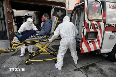 Nhân viên y tế chuyển bệnh nhân nhiễm COVID-19 lên xe cứu thương tại Toluca, Mexico. (Ảnh: AFP/TTXVN)