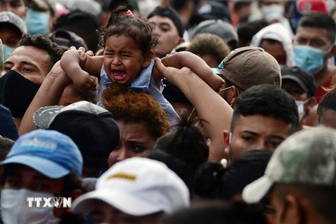Người di cư Honduras phá hàng rào cảnh sát để vào Guatemala tìm đường tới Mỹ tại khu vực biên giới Corinto, Honduras. (Ảnh: AFP/TTXVN)