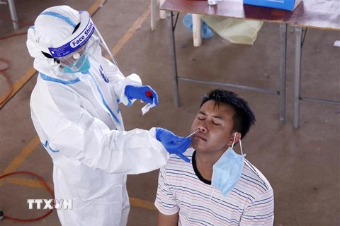 Bác sỹ lấy mẫu xét nghiệm cho một người dân Vientiane tại một điểm xét nghiệm dã chiến. (Ảnh: Phạm Kiên/TTXVN)