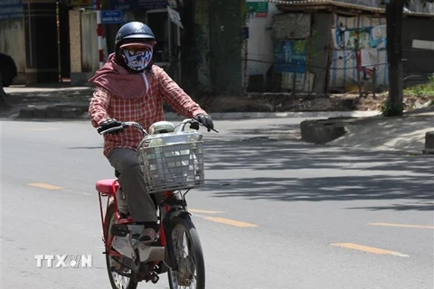 Người tham gia giao thông phải mặc đồ bảo hộ kín người, để tránh nắng nóng. (Ảnh: Nguyên Lý/TTXVN)