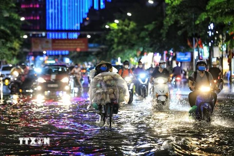 Người dân Hà Nội di chuyển khó khăn sau cơn mưa lớn. (Ảnh: Thành Đạt/TTXVN)