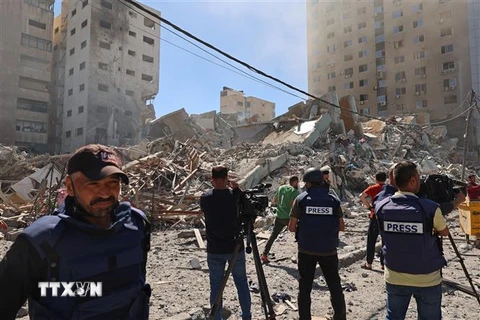 Các phóng viên tại hiện trường đổ nát của Toà tháp Jala, nơi đặt văn phòng một số hãng truyền thông quốc tế, sau khi máy bay Israel oanh tạc Dải Gaza, ngày 15/5. (Ảnh: AFP/TTXVN)