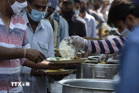 Người dân nhận thức ăn từ thiện trong bối cảnh dịch COVID-19 hoành hành tại Hyderabad, Ấn Độ. (Ảnh: AFP/TTXVN)