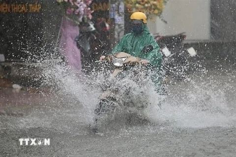 Người dân vất vả di chuyển giữa làn nước ngập sâu trên đường Ung Văn Khiêm (quận Bình Thạnh, Thành phố Hồ Chí Minh). (Ảnh: Hồng Giang/TTXVN)