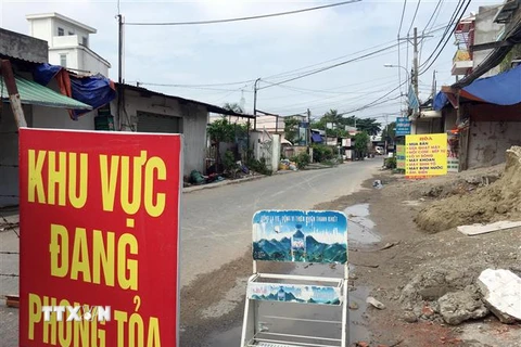 Lực lượng chức năng phong tỏa một đoạn đường TL19 (Khu phố 3B, phường Thạnh Lộc, Quận 12, Thành phố Hồ Chí Minh). (Ảnh: Tiến Lực/TTXVN)