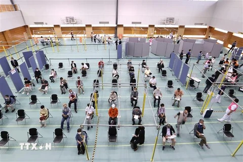 Người dân chờ tiêm vaccine ngừa COVID-19 tại trung tâm tiêm chủng ở thành phố Toyoake, quận Aichi, Nhật Bản. (Ảnh: AFP/TTXVN)