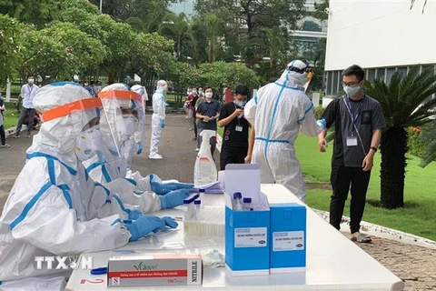 Các y bác sỹ Trung tâm kiểm soát bệnh tật Tp Hồ Chí Minh và Quận 7 thực hiện xét nghiệm sàng lọc COVID-19 ngẫu nhiên cho công nhân ở Khu chế xuất Tân Thuận. (Ảnh: Thanh Vũ/TTXVN)