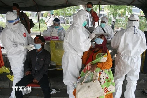 Nhân viên y tế lấy mẫu xét nghiệm COVID-19 cho người dân tại Surabaya, Đông Java, Indonesia. (Ảnh: THX/TTXVN)