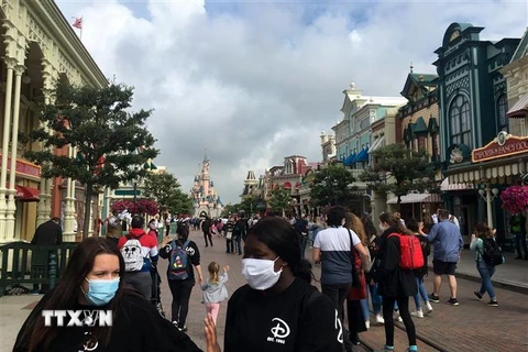 Du khách vẫn phải đeo khẩu trang khi tới thăm công viên Disneyland ở thủ đô Paris. (Ảnh: AFP/TTXVN)