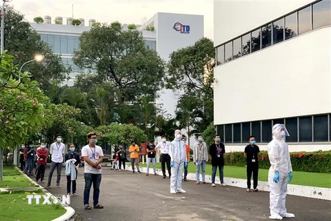 Công nhân Công ty TNHH CCH TOP Việt Nam tại Khu chế xuất Tân Thuận chờ lầy mẫu xét nghiệm sàng lọc COVID-19. (Ảnh: Thanh Vũ/TTXVN)