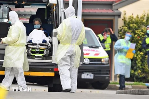 Nhân viên y tế chuyển bệnh nhân nghi mắc COVID-19 lên xe cứu thương tại bang Victoria, Australia. (Ảnh: AFP/TTXVN)