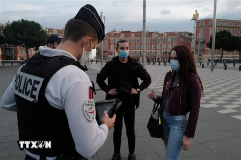 Cảnh sát kiểm tra giấy tờ của người lưu thông trên đường phố. (Ảnh: AFP/TTXVN)