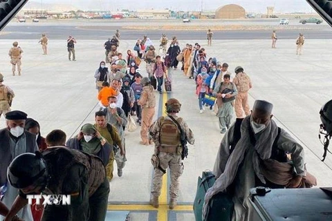 Người dân được lực lượng an ninh hỗ trợ lên máy bay sơ tán khỏi Afghanistan, tại sân bay quốc tế ở Kabul. (Ảnh: Reuters/TTXVN)