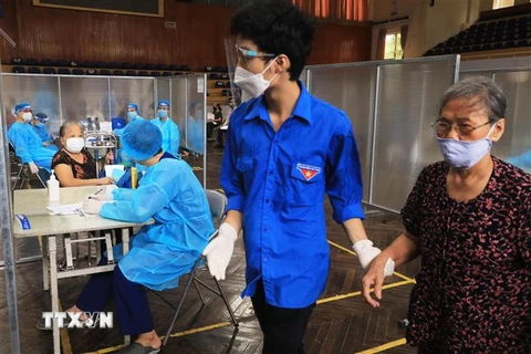 Người cao tuổi được đội ngũ thanh niên tình nguyện chăm sóc tận tình tại điểm tiêm vaccine phòng COVID-19. (Ảnh: Lâm Khánh/TTXVN)