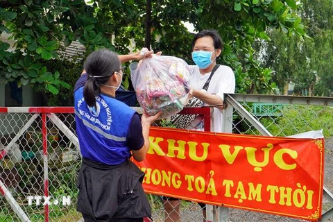 Trao túi an sinh cho người dân khu vực phong tỏa. (Ảnh: Xuân Khu/TTXVN)