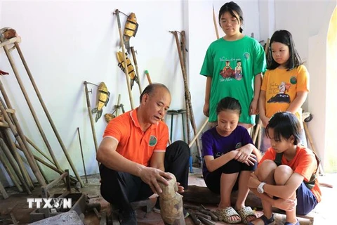 Nghệ nhân Nguyễn Thành Lai, trưởng phường rối nước Luy Lâu, giới thiệu con rối đến với các em học sinh. (Ảnh: Thanh Thương/TTXVN)