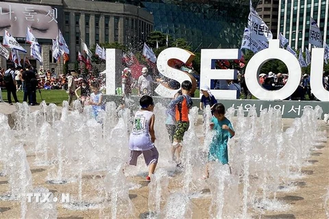 Trẻ em Hàn Quốc vui đùa tại đài phun nước tại Quảng trường trước Tòa thị chính Seoul dưới cái nắng gần 40 độ C. (Ảnh: Anh Nguyên/TTXVN)