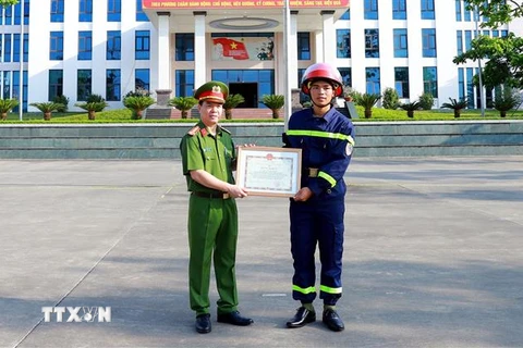 Đại tá Đỗ Tiến Thùy, Phó Giám đốc Công an tỉnh Tuyên Quang, trao Bằng khen của Chủ tịch UBND tỉnh cho chiến sỹ Quan Ngọc Hoàng. (Ảnh: Quang Cường/TTXVN)