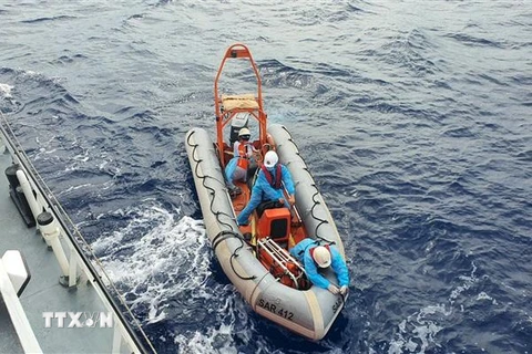 Nhân viên tàu SAR 412 dùng canô tiếp cận tàu cá ứng cứu một thuyền viên gặp nạn. (Ảnh: TTXVN phát)