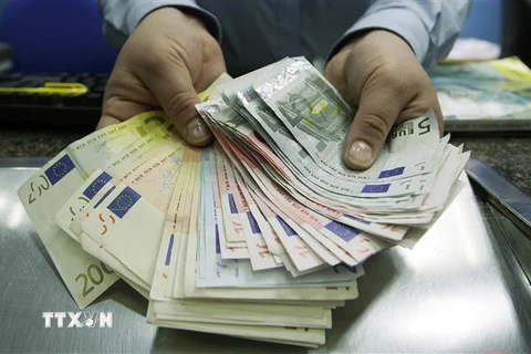 Nhân viên giao dịch ngoại hối kiểm đồng euro tại London, Anh. (Ảnh: AFP/TTXVN)