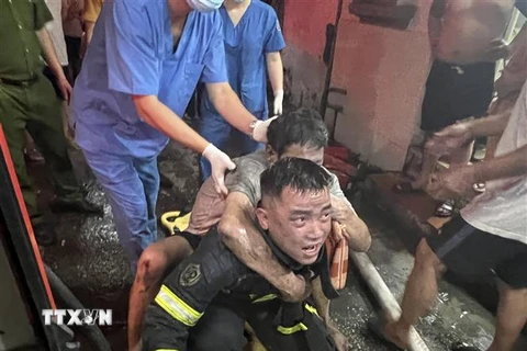 Lực lượng Cảnh sát Phòng cháy chữa cháy và cứu nạn cứu hộ đưa người bị nạn ra khỏi đám cháy. (Ảnh TTXVN phát)