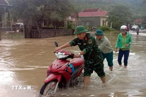 Lực lượng vũ trang huyện Quỳnh Lưu hỗ trợ người dân địa phương đi qua các đoạn bị ngập nước. (Ảnh: TTXVN phát)