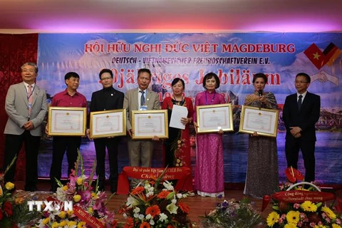 Phó Đại sứ, Tham tán Công sứ Chu Tuấn Đức tại CHLB Đức tặng hoa và trao giấy khen cho những thành viên có nhiều đóng góp cho Hội hữu nghẹ Đức-Việt 30 năm. (Ảnh: Phương Hoa/TTXVN)