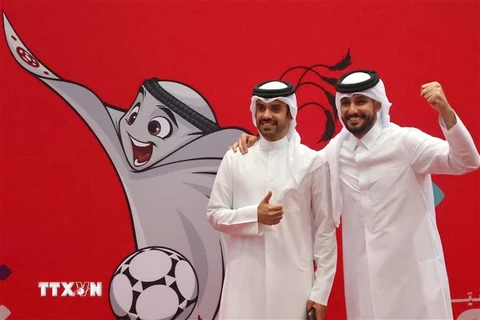 Người dân chụp ảnh bên hình ảnh linh vật World Cup Qatar 2022 ở Doha. (Ảnh: AFP/TTXVN)