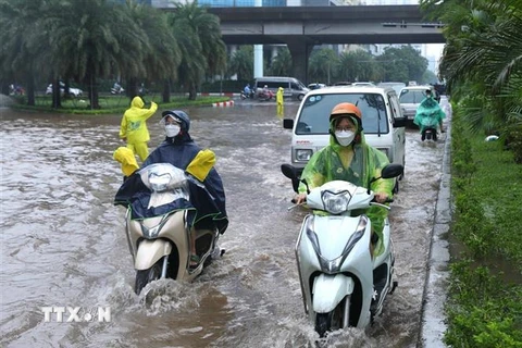 Các phương tiện đi lại khó khăn trong điều kiện ngập lụt do mua lớn. (Ảnh: Hoàng Hiếu/TTXVN)