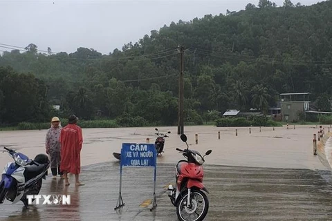 Lực lượng chức năng huyện Đồng Xuân gắn biển cảnh báo và cử lực lượng chức năng chốt chặn tại một tuyến đường bị ngập trong nước lũ. (Ảnh: TTXVN phát)