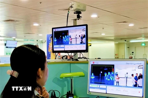 Nhân viên sân bay Tân Sơn Nhất kiểm tra màn hình hiển thị máy quét thân nhiệt đối với hành khách quốc tế đến Việt Nam. (Ảnh: Đinh Hằng/TTXVN)