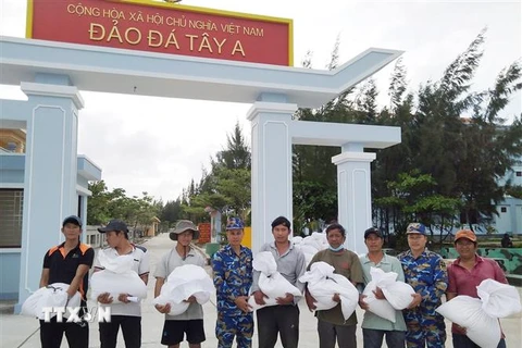 Cán bộ, chiến sỹ đảo Đá Tây đang hỗ trợ gạo cho bà con ngư dân tỉnh Ninh Thuận. (Ảnh: TTXVN phát)