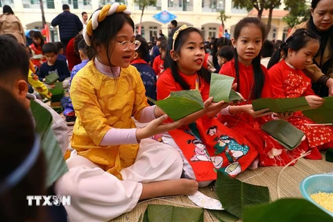 Các em nhỏ rất hào hứng khi được tham gia trải nghiệm gói bánh chưng đón Tết. (Ảnh: Huy Hùng/TTXVN)