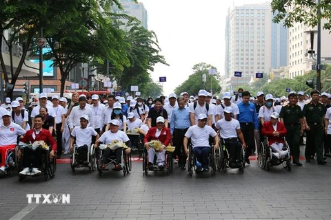 Các đại biểu cùng đông đảo vận động viên khuyết tật 19 tỉnh thành phố trong cả nước tham gia đi bộ đồng hành tại chương trình chào mừng ngày người khuyết tật Việt Nam (18/4). (Ảnh: Thanh Vũ/TTXVN)