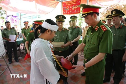 Trung tướng Nguyễn Duy Ngọc, Thứ trưởng Bộ Công an, trao quyết định của Bộ trưởng Bộ Công an về việc truy thăng cấp bậc hàm từ Thiếu tá lên Trung tá đối với chiến sỹ Nguyễn Xuân Hào. (Ảnh: TTXVN phát)