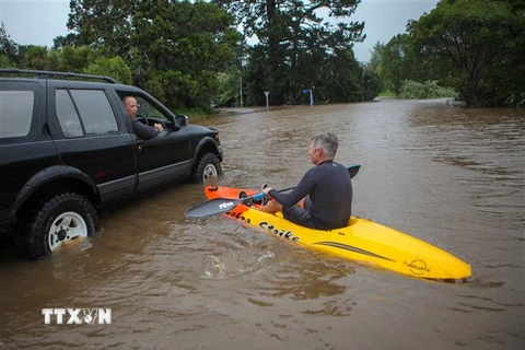 Người dân di chuyển trên đoạn đường ngập lụt do ảnh hưởng của bão Gabrielle tại Auckland, New Zealand ngày 14/2. (Ảnh: THX/TTXVN)
