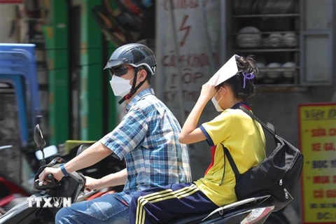 Người phải di chuyển dưới nắng nóng, nền nhiệt cao ngoài trời dễ gây nên tình trạng sốc nhiệt, mất nước, kiệt sức... (Ảnh: Hoàng Hiếu/TTXVN)