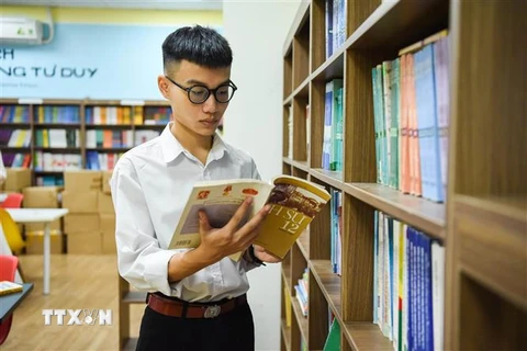 Nguyễn Viết Khôi Nguyên đọc sách tại thư viện trường Trung học phổ thông Nguyễn Văn Cừ. (Ảnh: TTXVN phát)