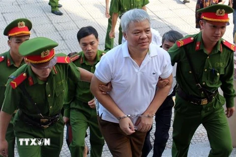 Lực lượng chức năng dẫn giải bị cáo Nguyễn Văn Khuê vào phòng xét xử. (Ảnh: Vũ Hà/TTXVN)