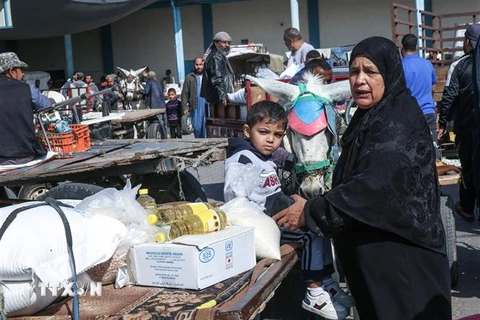 Người dân Palestine nhận lương thực cứu trợ tại một trung tâm phân phối của Cơ quan cứu trợ và hành động của Liên hợp quốc (UNRWA) tại trại tị nạn ở Rafah, Dải Gaza. (Ảnh: AFP/TTXVN)